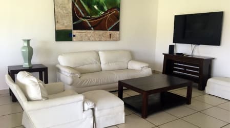 Modern living room with white sofas, flat screen TV and art in coastal VistaMar villa Panama