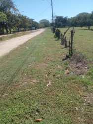 Dirt road next to open lot with fencing and utility poles in rural Bejuco Panama