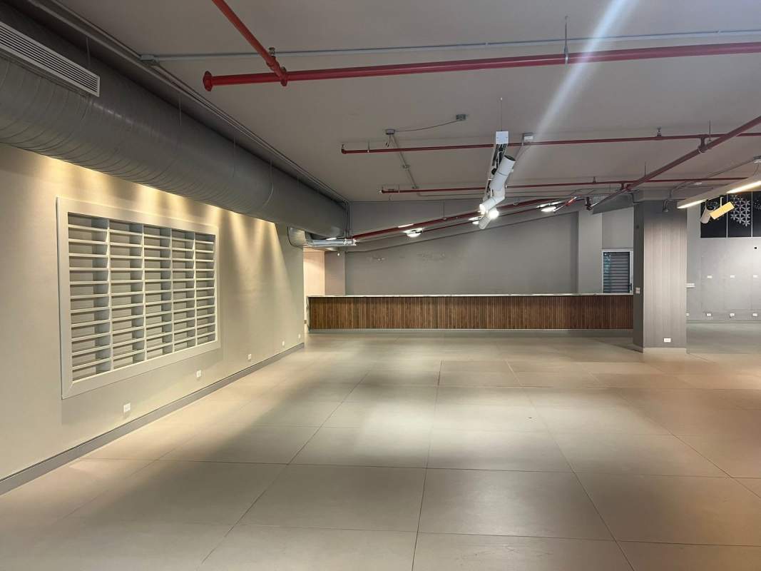 Open commercial interior large tiled floors exposed ceiling pipes glass railings accent walls Obarrio Panama