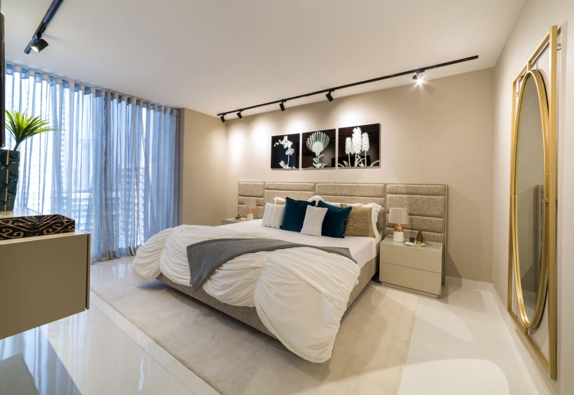 Modern bedroom with upholstered bed, gold mirror, large windows PH Cangrejo Suites Panama