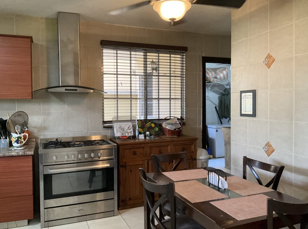 Bright kitchen with marble countertop, appliances, wood cabinetry at Castel Novo home Panama City