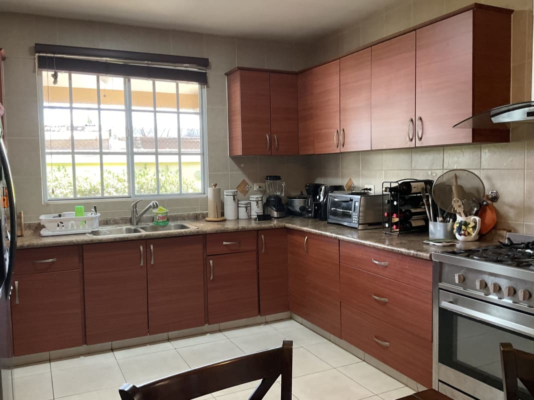 Kitchen with wood cabinets, window blinds, stainless stove, dining table Castel Novo house Panama