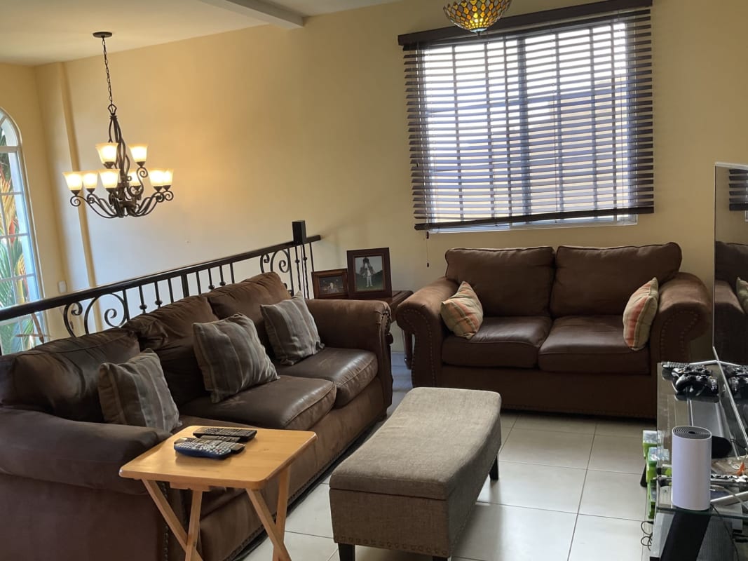 Living room brown sofas ottoman window blinds chandelier Castel Novo Panama