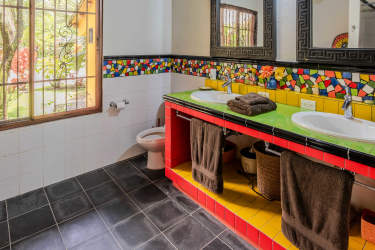 Rustic Mediterranean style bathroom with tiled bathtub and window garden view in mountain property