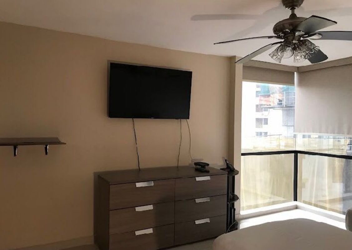 Modern bedroom with mounted TV, large windows, and AC in PH Royal Princess Paitilla Panama