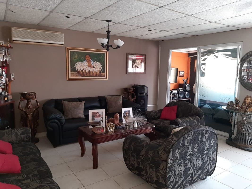 Living room with black leather sofa, patterned armchairs, sliding glass doors, decor Praderas del Rocio Panama