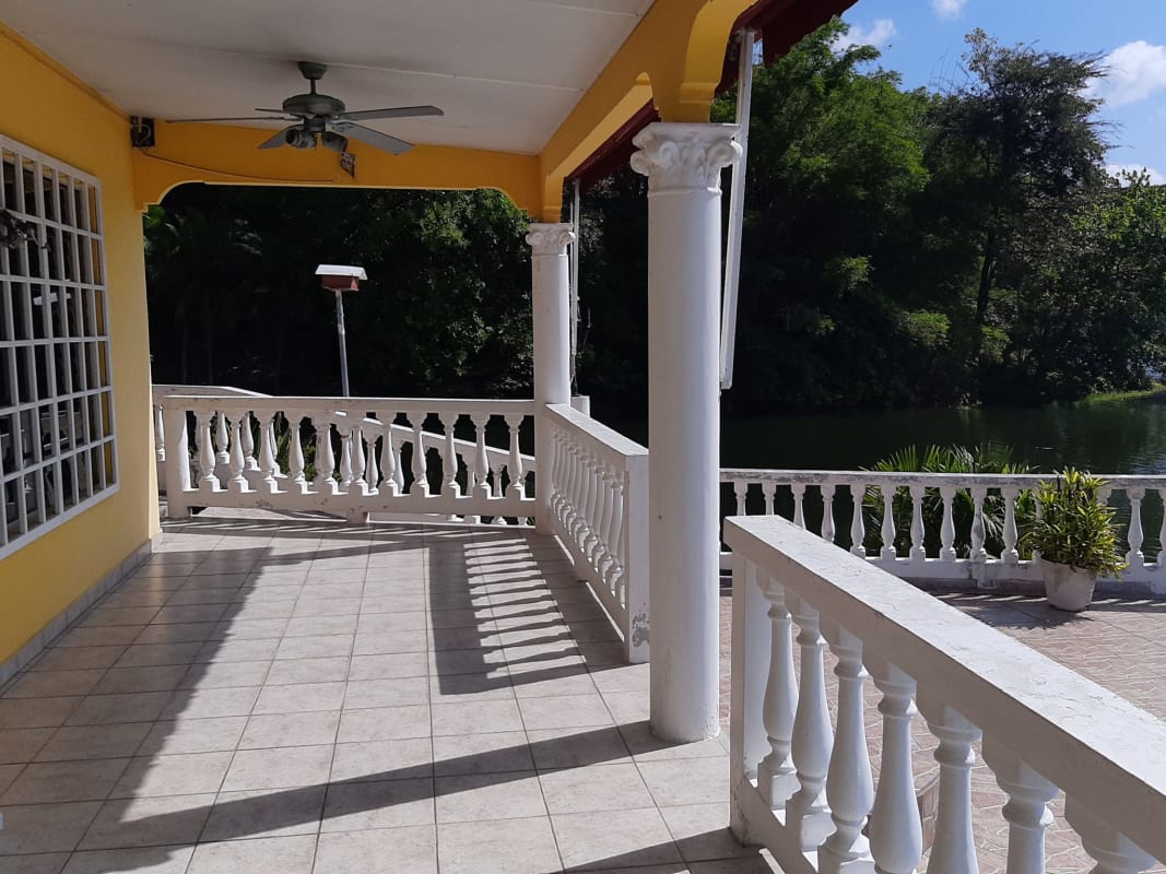 Large covered terrace with columns overlooking lake and gardens in Las Cumbres Panama