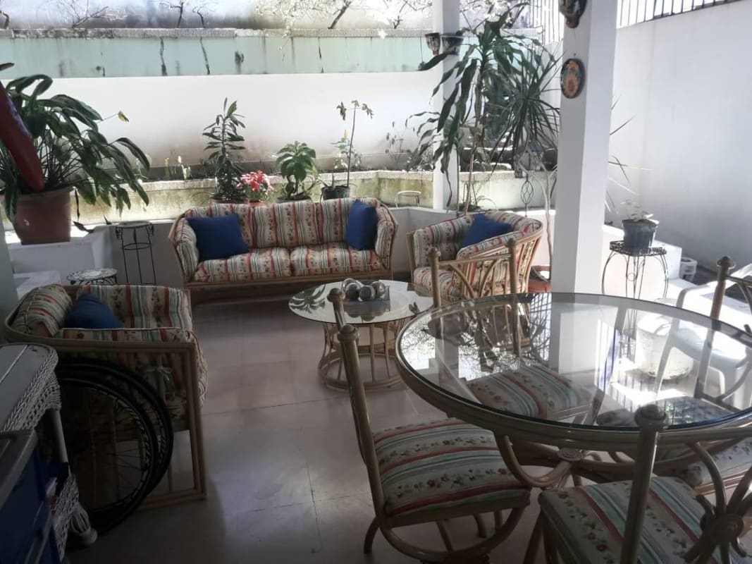 Sunny indoor patio with rattan furniture, plants, glass dining table, La Loma Panama City