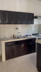 Kitchen with dark wood cabinets, beige tile backsplash, double sink in Las Lomas David Chiriquí