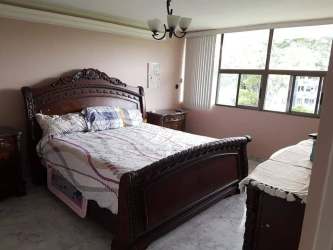 Bedroom with pink walls, large window, carved wood furniture in Espinar Colón Panama apartment