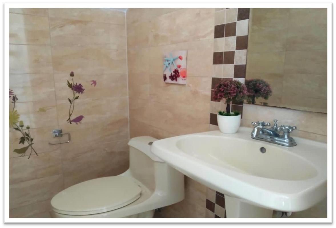 Bathroom with beige mosaic tile pedestal sink wall art PH Augusta Brisas del Golf