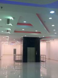 Lobby hall with central elevator and colorful ceiling accents in multi-story commercial building Panama