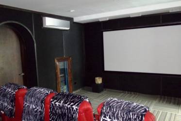 Dedicated home theater with projection screen, red recliners, modern decor Vistamar San Carlos