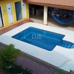 Main swimming pool with palm trees volleyball net and lounge chairs in fenced income property Nueva Gorgona Panama