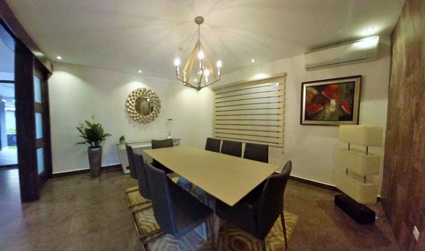 Modern dining room with elegant chandelier, dining set, accent mirror, and artwork in Panama family home