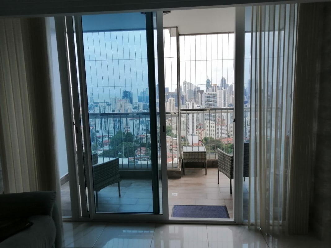 Living room with large glass doors overlooking balcony city view in Pacific Park Plaza Panama