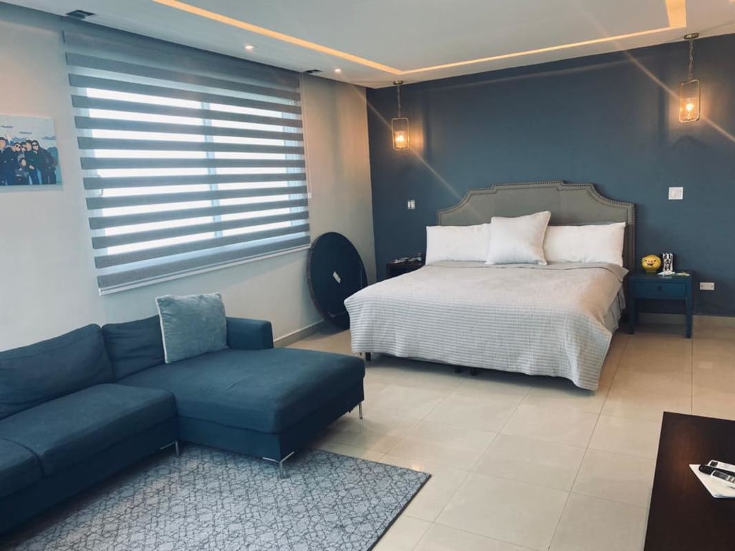 Bright bedroom with large bed, blue wall accent and urban views at PH Zeus luxury condo Panama