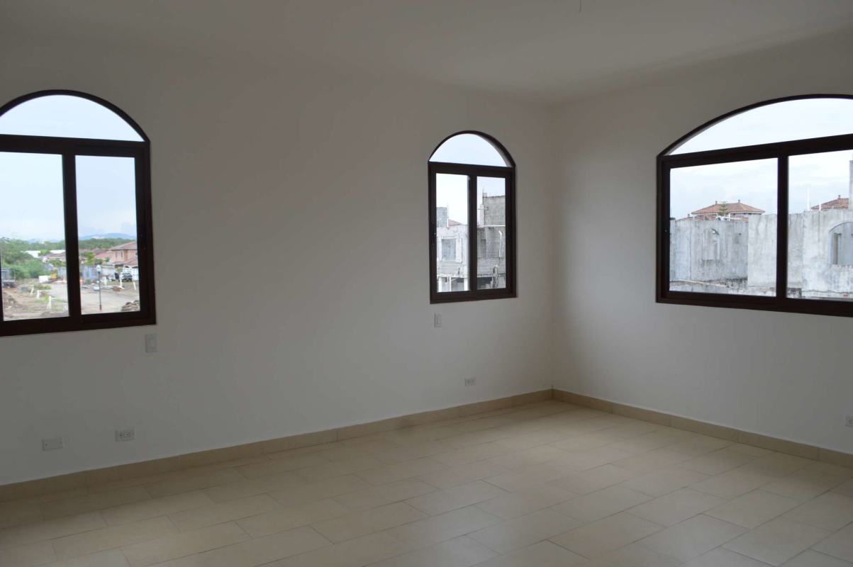 Living room in new Costa Sur home with tile floors and large arched windows, urban view