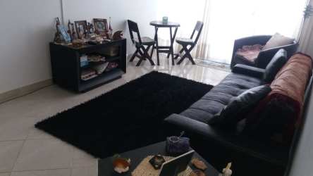 Open living and dining area with black sofa, large window, dining table Playa Corona Panama