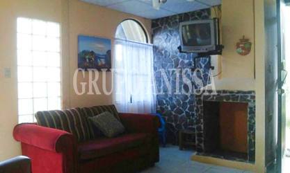 Living room with stone fireplace, sofa and television in cabin Altos del Cerro Azul Panama