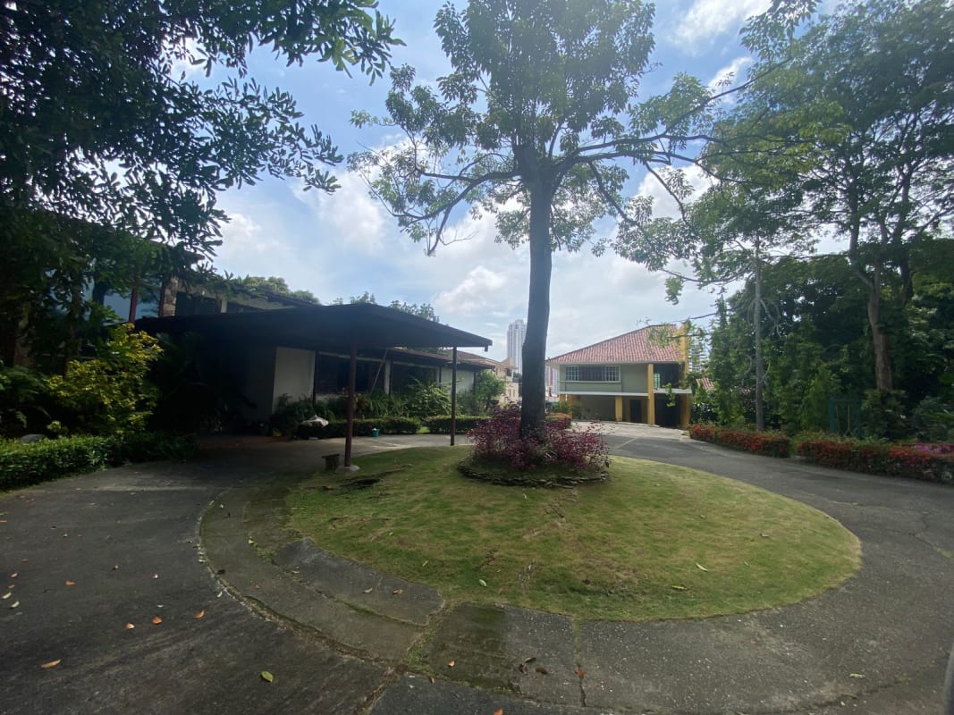 Lush mature landscape surrounds circular driveway at elevated Panama property in Urbanización La Loma
