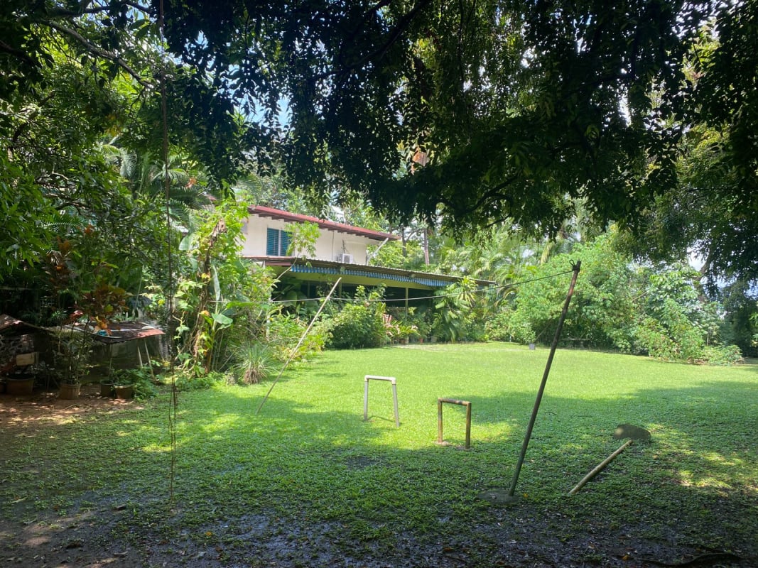 Tropical style two-story house with red tile roof and grassy yard in Pedregal Panama