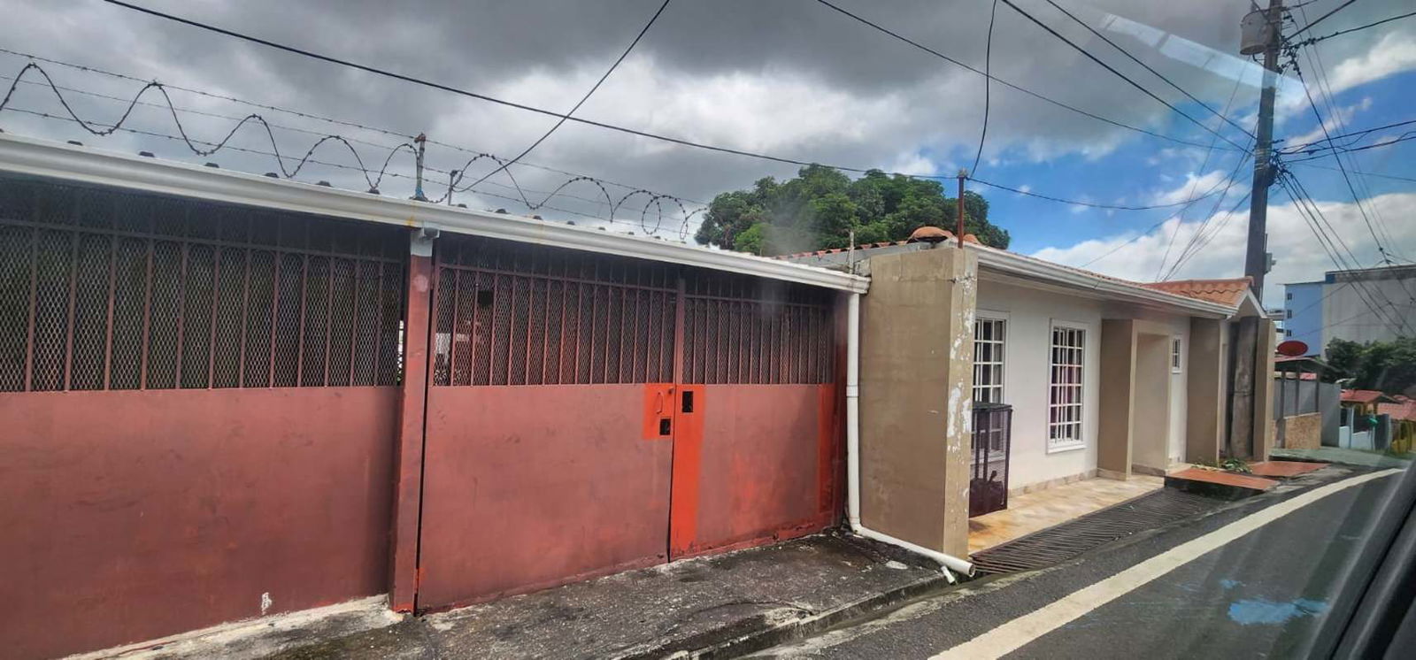Entrance with metal gate, white facade, tiled roof house in Pedregal Panama