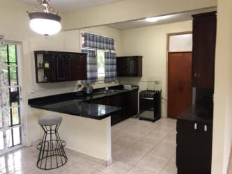 Kitchen with dark wood cabinets, granite counters and breakfast island in family house Howard Panama