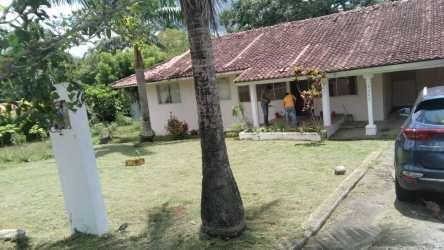 Single-story house with covered porch, red tile roof and grassy garden in gated Howard area Panama