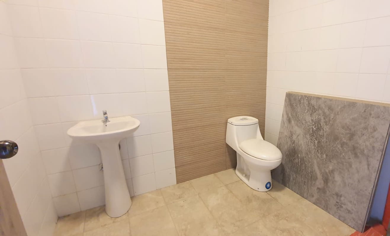 Minimalist bathroom with white tiles pedestal sink in Plaza Midtown commercial space Panama City
