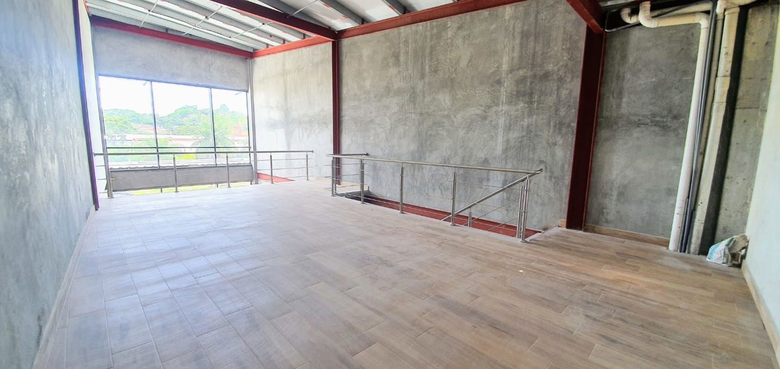 Mezzanine loft workspace with large window and metal railings Plaza Midtown Panama City