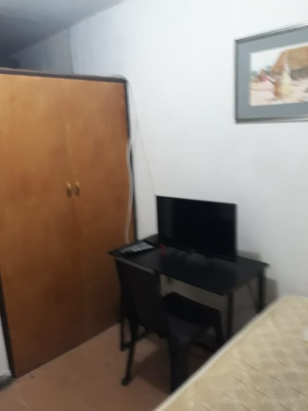 Cozy small bedroom with wardrobe, desk, and TV on wall in Villa de las Fuentes Panama City