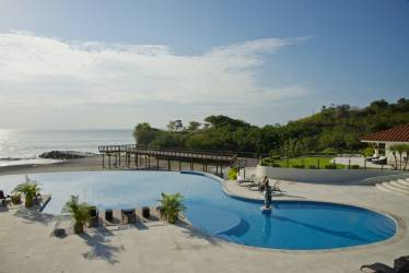 Infinity pool overlooking Pacific Ocean with pier and lush gardens in Vista Mar Beach Golf Marina Panama