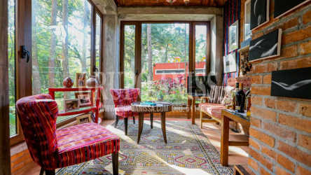 Rustic yellow cabin with large windows amid lush gardens on Altos del María mountain estate Panama