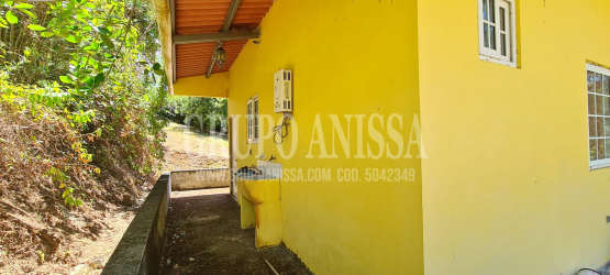 Yellow color cabin with sloped red roof and lush greenery in Altos del María mountain community Panama