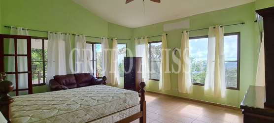 Bedroom with vaulted ceilings, light green walls, large windows in mountain home Altos del María Panama