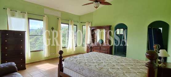 Large master bedroom with light green walls, big windows scenic garden view Altos del María Panama