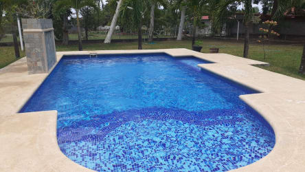 Private swimming pool surrounded by palm trees and garden at vacation country house in Panama