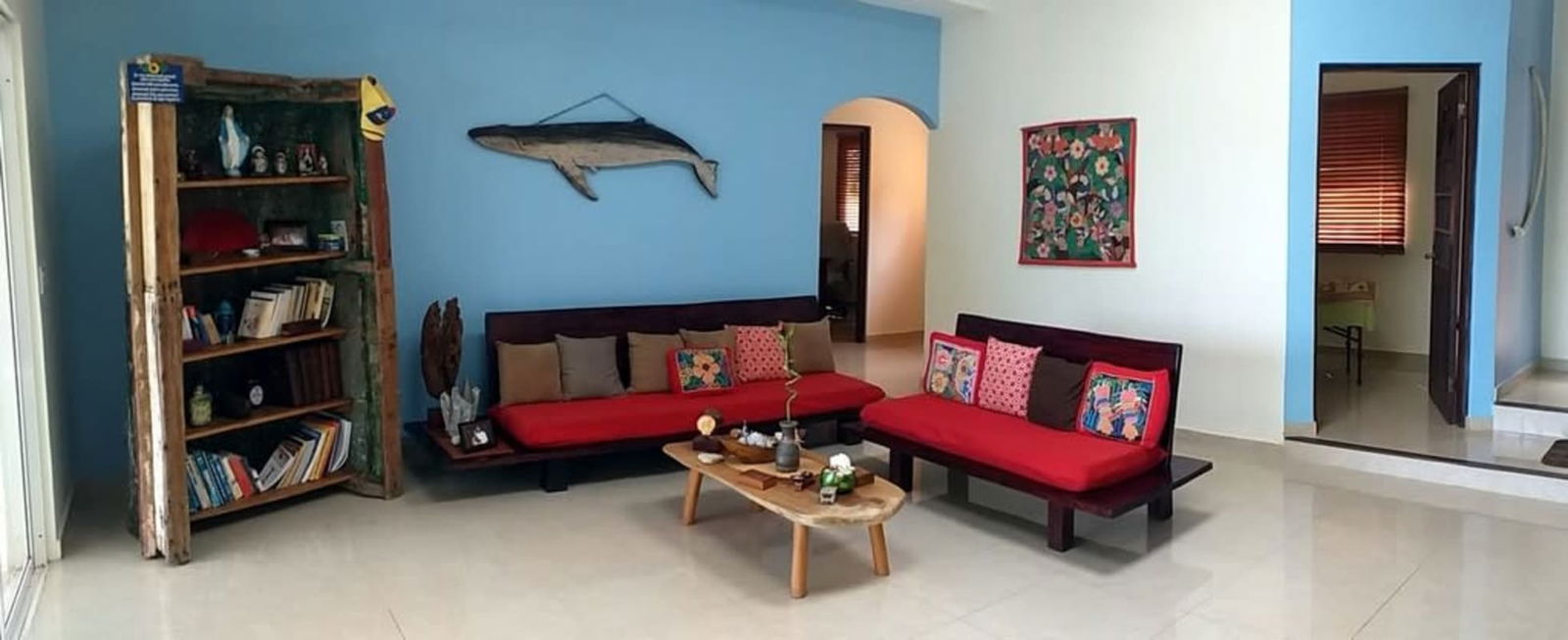 Living room featuring blue accent wall rustic bookshelf wooden sofas tropical design Isla Saboga Las Perlas Panama