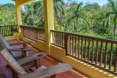 Covered ocean-view balcony with wooden seating, lush greenery at Azueros Ocean Loft Pedasi Panama