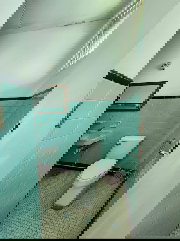 Large grassy fenced yard with privacy wall and neighboring buildings in Parque Lefevre house Panama City