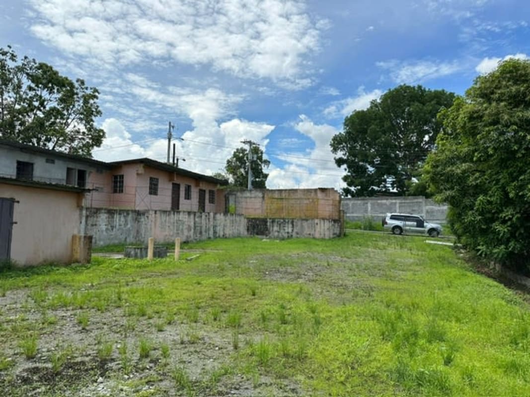 Vacant grassy lot bordered by walls with trees and small building, located in Altos de Tocumen Panama