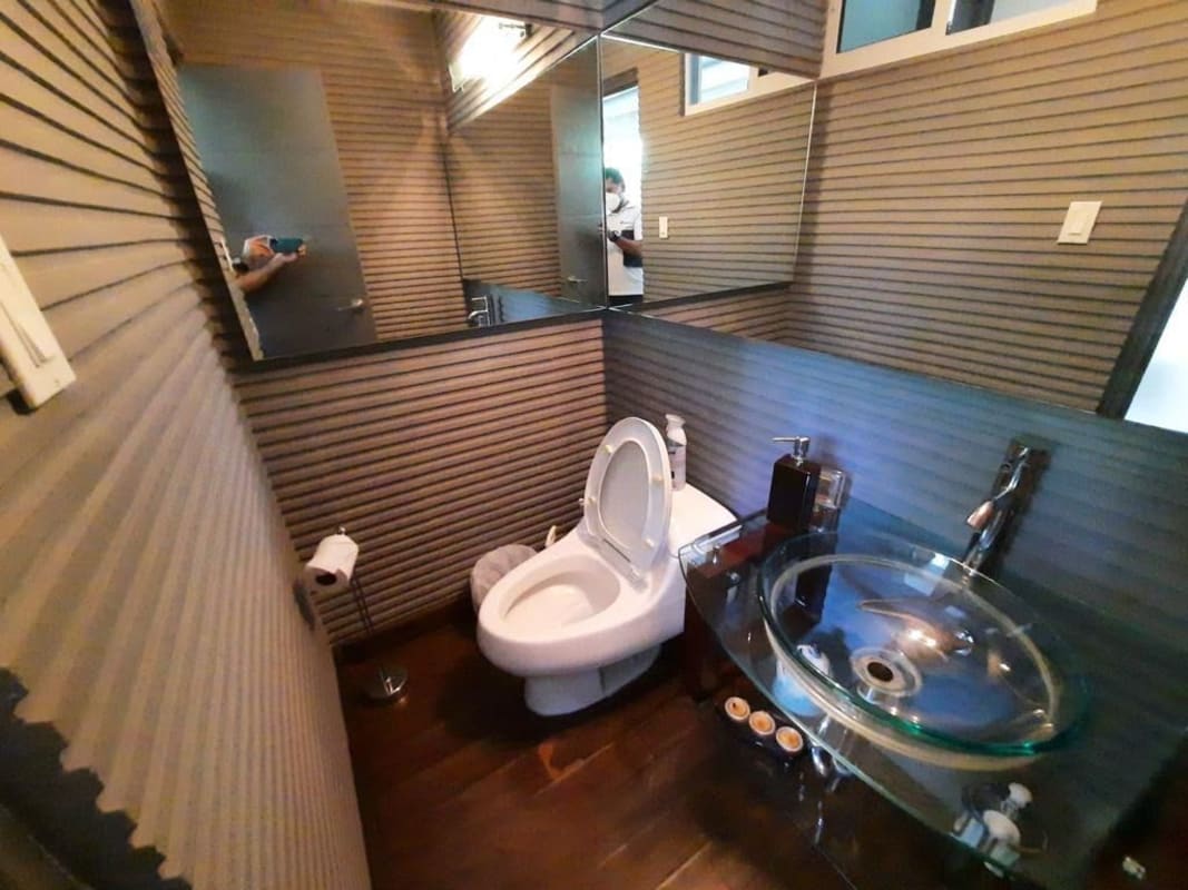 Modern lounge with built-in home bar, glass shelving, and wood floors for sale Panama City