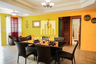 Colorful dining room with vibrant yellow walls and wicker furniture in mountain house Panama