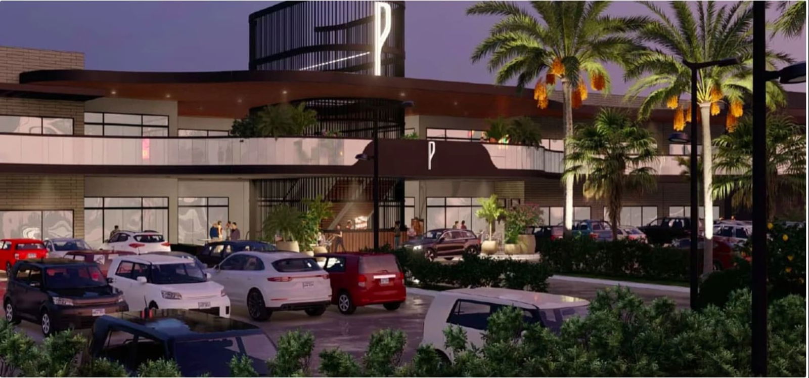 Modern two-story commercial building illuminated at night with parking and palm trees at Plaza Paseo Drive Brisas del Golf