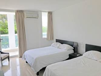 Bright modern bedroom with large windows and two beds in Playa Blanca Resort Panama