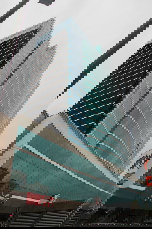 Exterior high-rise commercial building with blue-tinted glass facade and retail stores on ground floor Panama