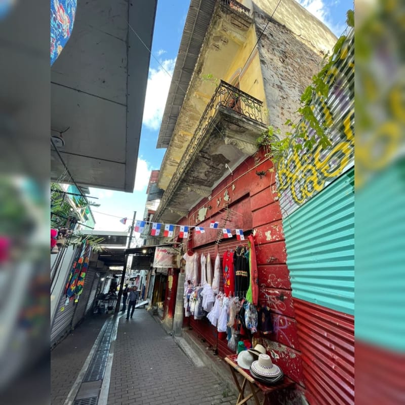 Exterior shopfronts with arched doors and clothing vendors in colonial commercial building Santa Ana