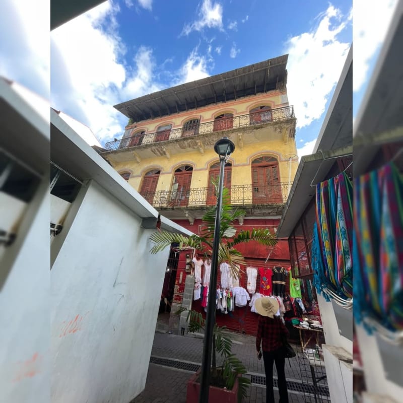 Weathered colonial commercial corner building with iron balconies overlooking market stalls in Santa Ana Panama City