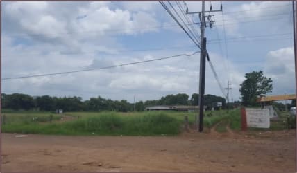 Rural area with dirt road, electricity poles and grassy land beside Pan-American Highway in El Roble Aguadulce